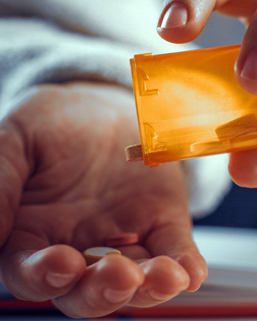 A hand tipping high-dose melatonin pills out of a prescription bottle